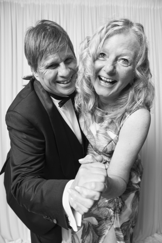 A couple dance cheek to cheek, both laughing