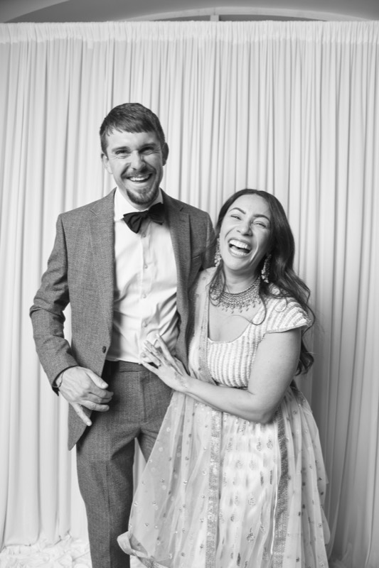 A couple laugh together, she leans into his shoulder